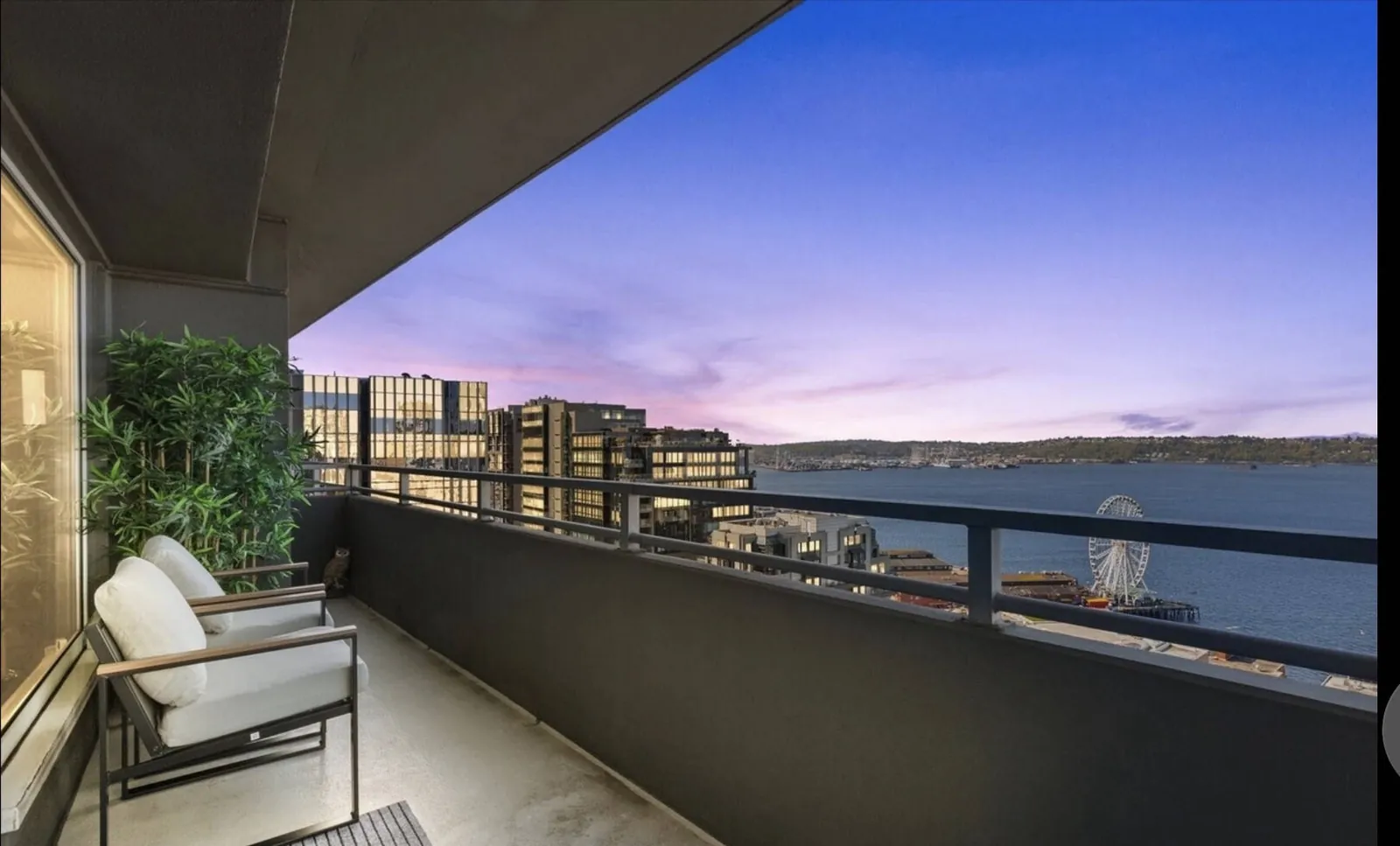Private balcony at the OceanView condo at dusk, looking over Elliott Bay and the Seattle Great Wheel